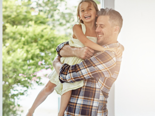 Man holding daughter as he walks into a short term rental home